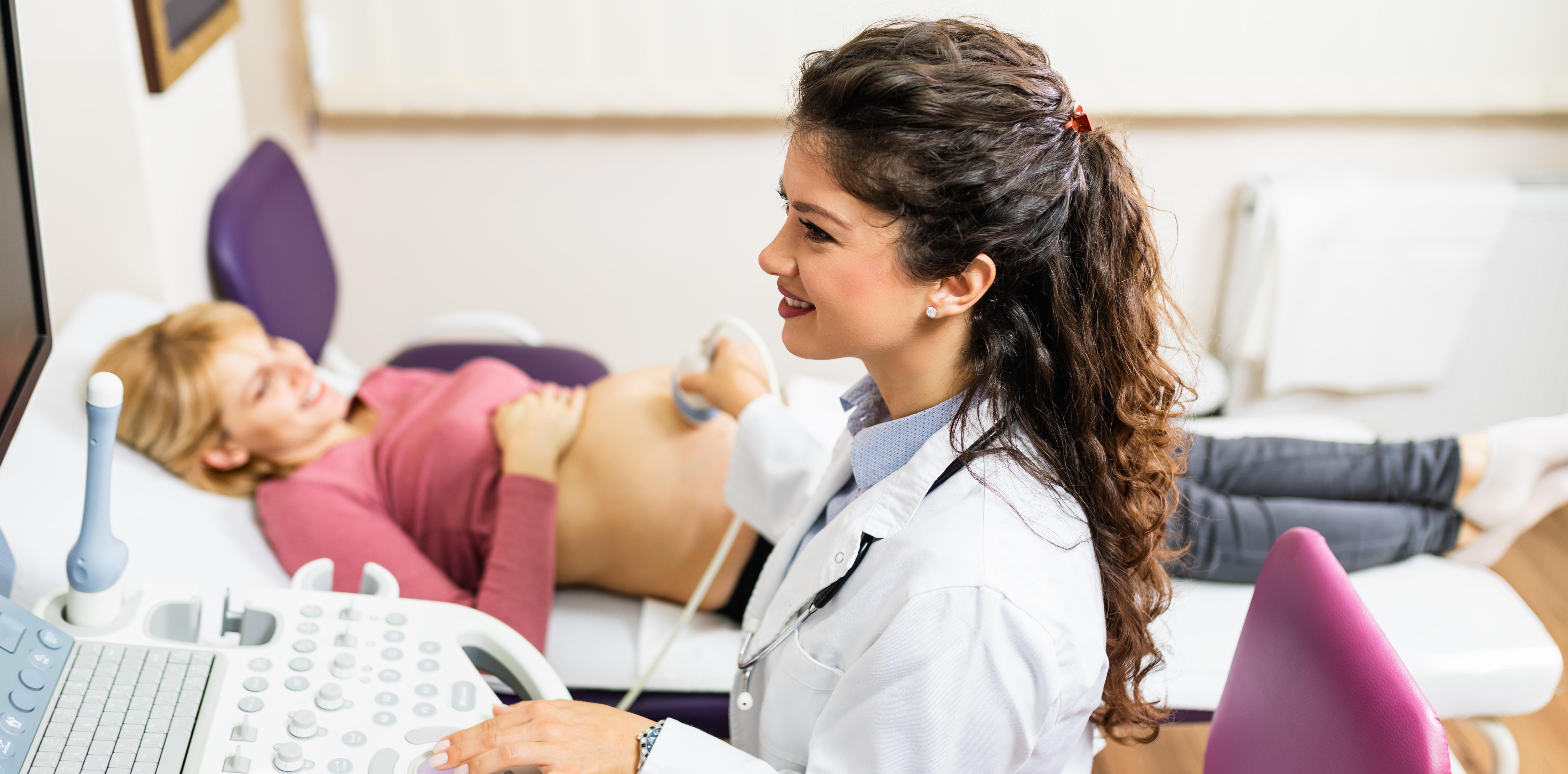 产科医生用超声波扫描检查孕妇腹部.